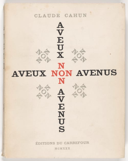 The French cover of Claude Cahun's Aveux non Avenus, an old book with a cream-colored background. The title is presented in a pattern, repeating itself backward and forward, up and down. "Non" appears in red, the letter "N" on four sides of a central "O." The other words, rendered in black, point out in the cardinal directions.